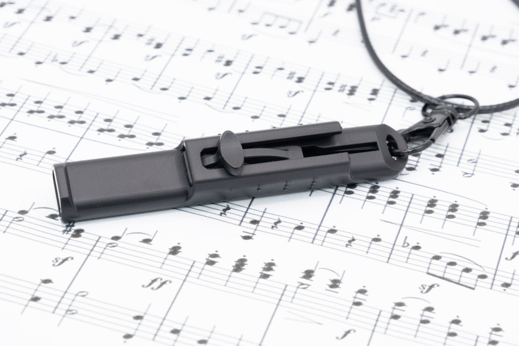 Vocal Trainer lying on printed sheet music with the necklace clip visible.