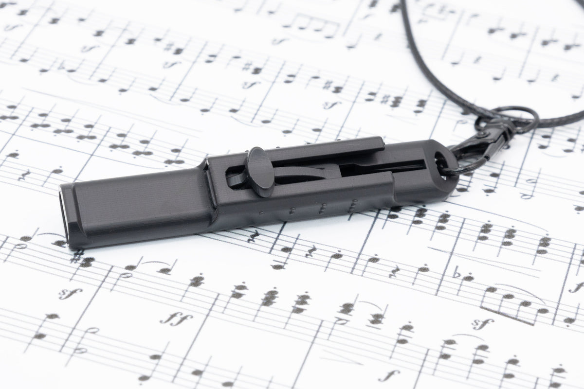 Vocal Trainer lying on printed sheet music with the necklace clip visible.